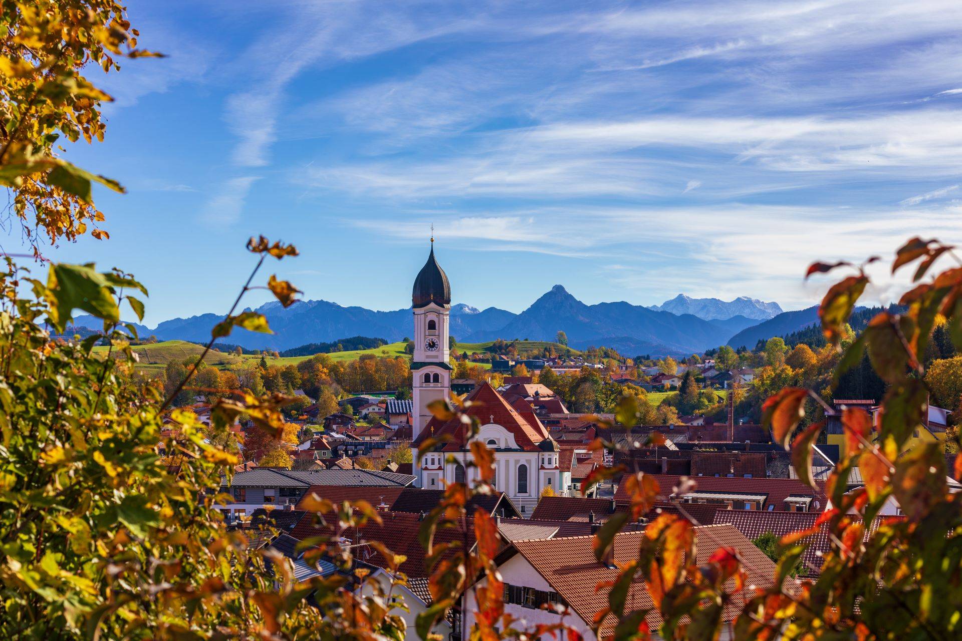 Kirche in Bayern vor Alpenkulisse im Herbst.