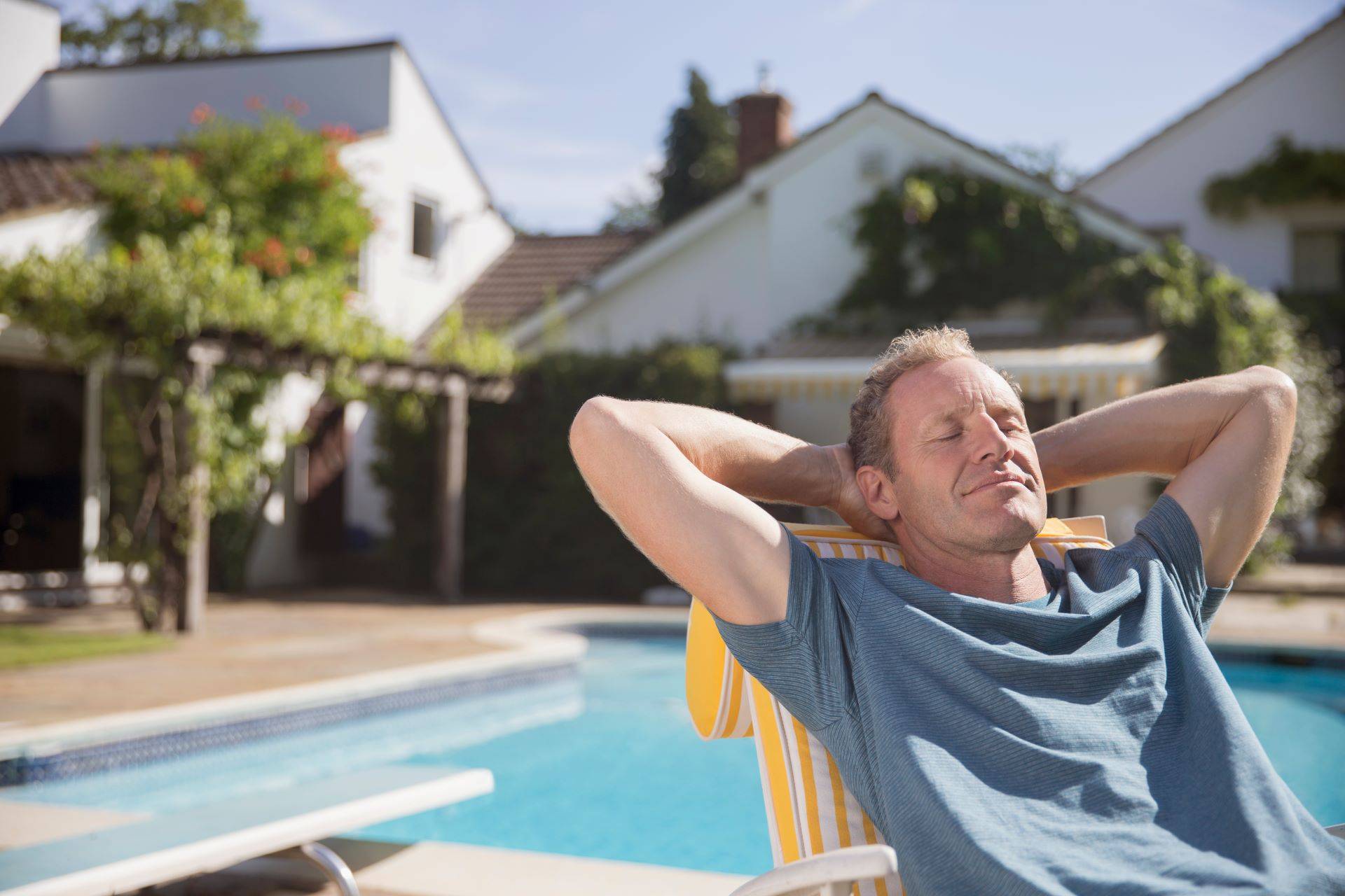 Entspannter Mann im Liegestuhl am Pool im sonnigen Garten